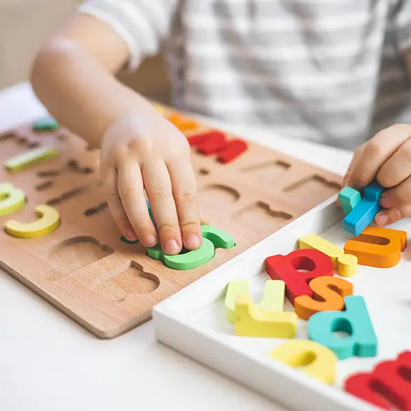 Skipwith Academy - junior kindergarten - child placing wooden letters into wooden alphabet board