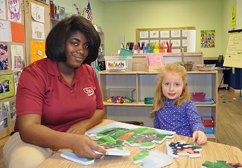 Childcare Jobs / Daycare Careers at Skipwith Academy - teacher in uniform smiling with child student