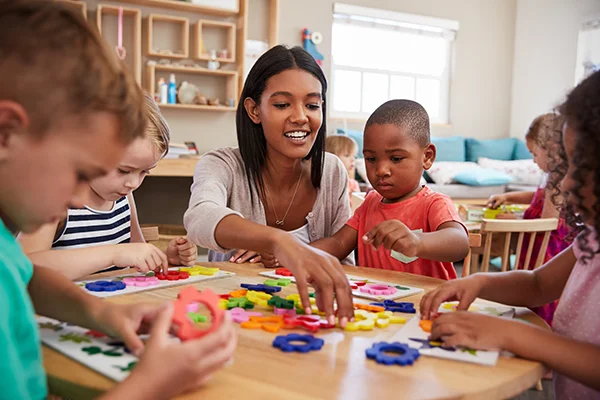 Skipwith Academy - Stepping Stones Montessori class - teacher assisting young children with Montessori learning tools